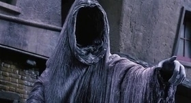 A cloaked, faceless figure with an outstretched arm appears in a dark, eerie setting. It’s the muppet ghost of Christmas future.