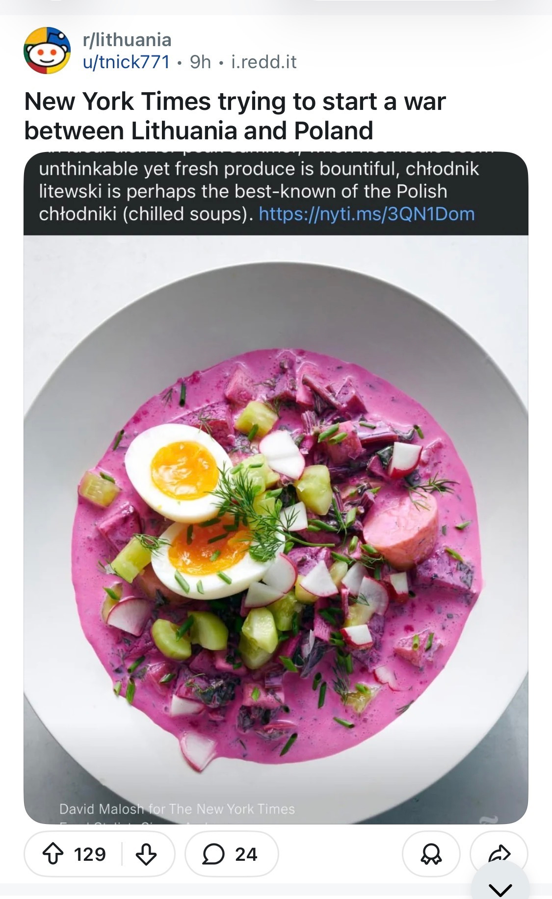 A screenshot from Reddit of a New York Times picture of a bowl of bright pink Lithuanian chilled soup, topped with a halved boiled egg, diced vegetables, and fresh herbs, is shown. The NYtimes caption erroneously labels it a Polish chilled soup. The Reddit poster comments “The New York Times is trying to start a war between Poland and Lithuania. 